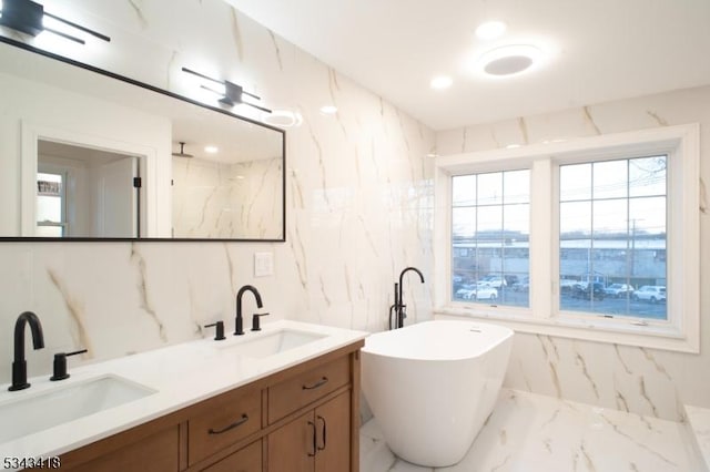 full bathroom with a freestanding bath, marble finish floor, a marble finish shower, and a sink