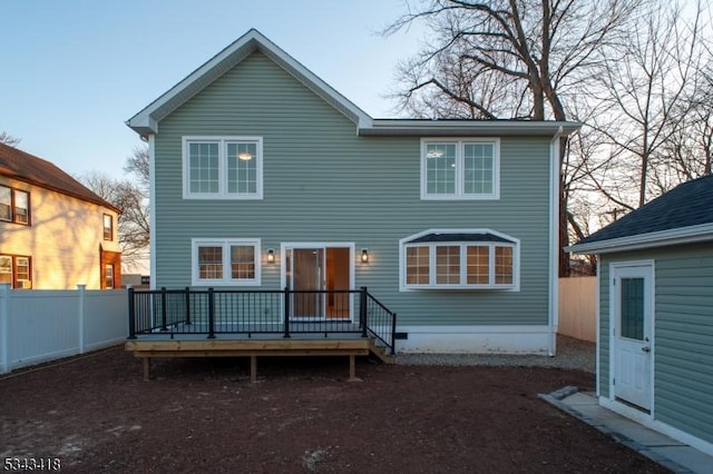 rear view of house with fence and a wooden deck