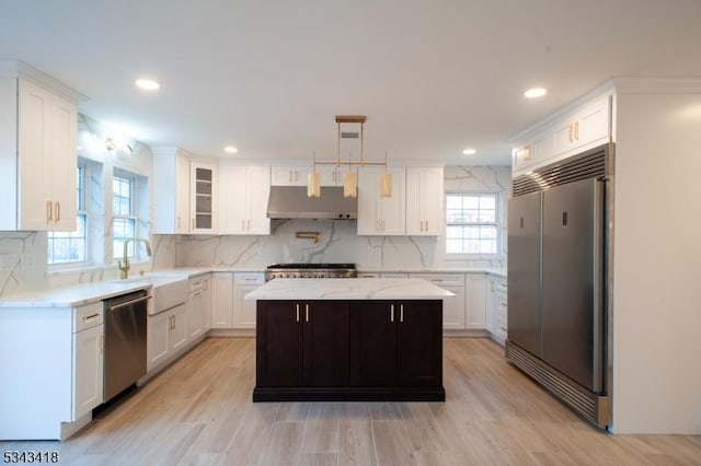 kitchen featuring under cabinet range hood, backsplash, appliances with stainless steel finishes, and a healthy amount of sunlight