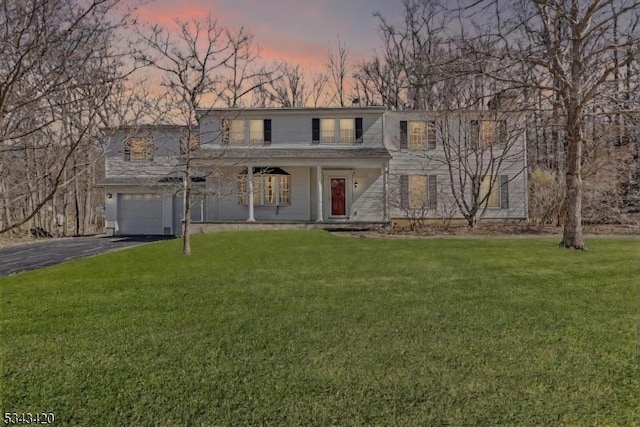 view of front facade with a porch, aphalt driveway, a garage, and a front yard