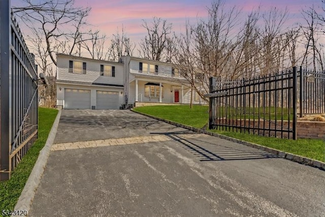 view of front of property with an attached garage, fence, a porch, a yard, and driveway