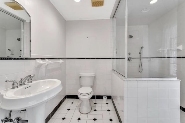 bathroom featuring visible vents, a sink, a walk in shower, tile patterned floors, and toilet