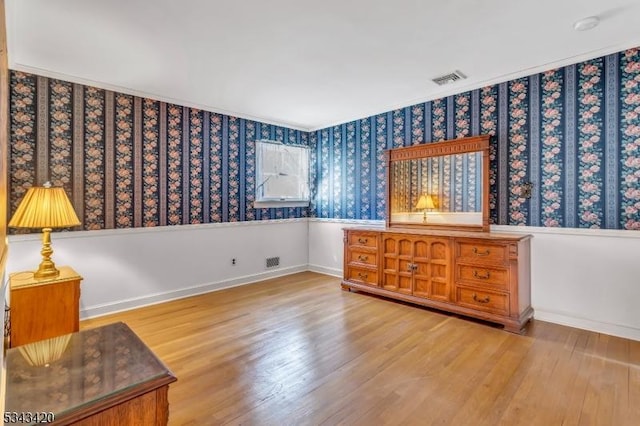 bedroom featuring visible vents, wallpapered walls, baseboards, and wood finished floors