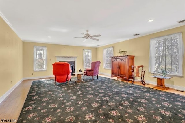 sitting room with plenty of natural light, visible vents, baseboards, and ceiling fan