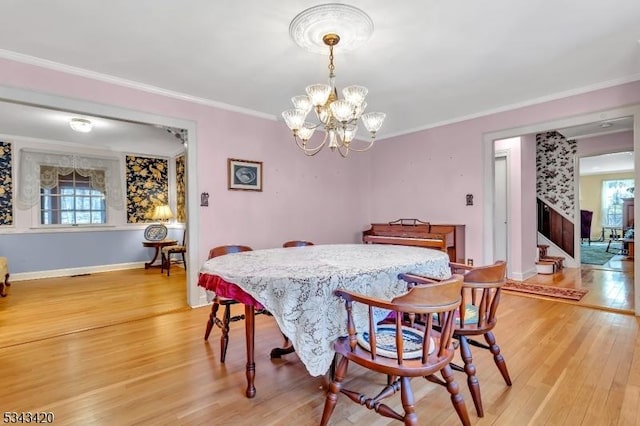 dining room with light wood-style flooring, plenty of natural light, ornamental molding, and a chandelier