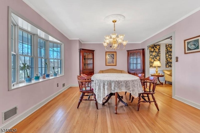 dining room with visible vents, a notable chandelier, light wood-style flooring, crown molding, and baseboards