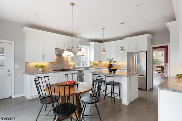 kitchen with hanging light fixtures, white cabinets, appliances with stainless steel finishes, and a center island