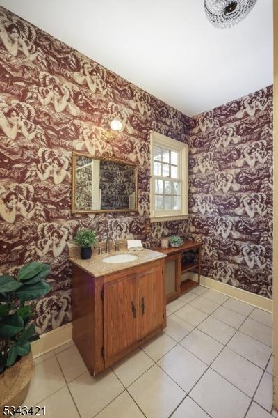 bathroom with wallpapered walls, vanity, baseboards, and tile patterned flooring