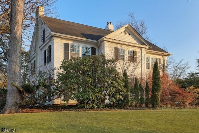 view of property exterior featuring a lawn and a chimney