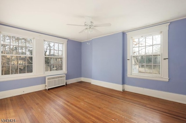 unfurnished room featuring plenty of natural light, radiator heating unit, baseboards, and hardwood / wood-style floors