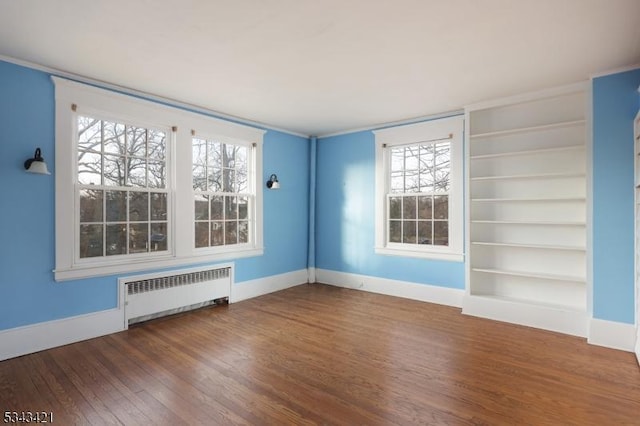 spare room featuring radiator, baseboards, and wood finished floors