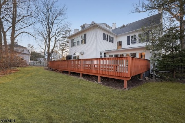 rear view of property featuring a yard, a wooden deck, and fence