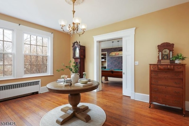 interior space with billiards, radiator, wood finished floors, and a chandelier