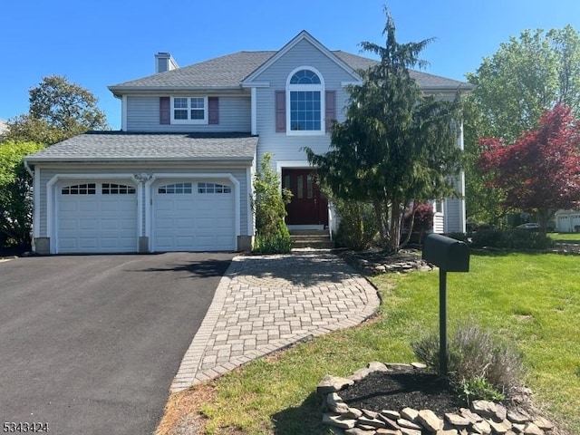 view of front of home featuring a front lawn, a shingled roof, a chimney, and aphalt driveway