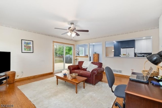 living room with light wood-style flooring, a ceiling fan, and baseboards