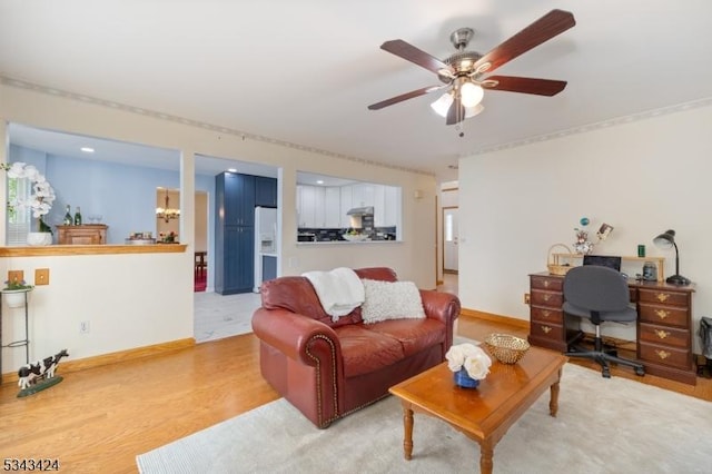 living area featuring light wood-type flooring, a ceiling fan, an office area, and baseboards