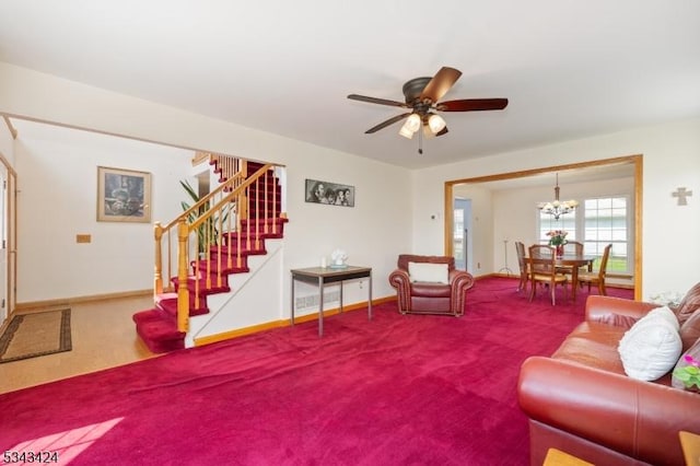 carpeted living area with stairway, a chandelier, ceiling fan, and baseboards
