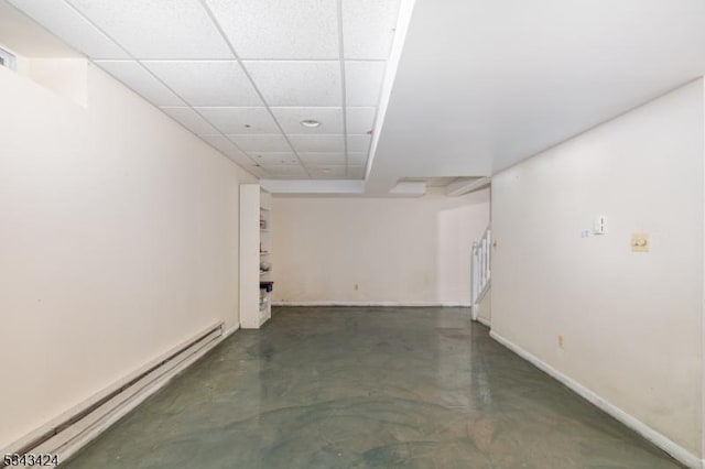 finished below grade area with a baseboard radiator, a paneled ceiling, stairs, and baseboards
