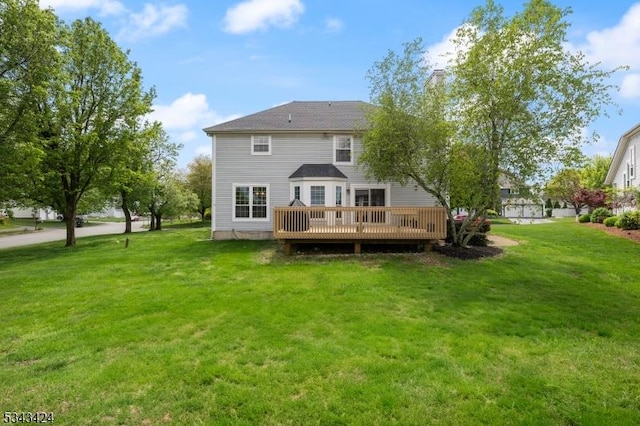 rear view of property featuring a wooden deck and a lawn