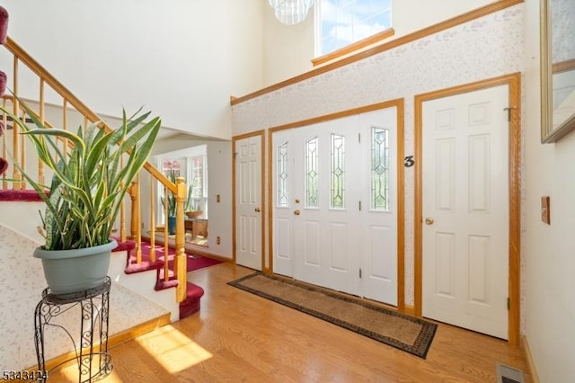 entrance foyer with stairway, wood finished floors, plenty of natural light, and a towering ceiling