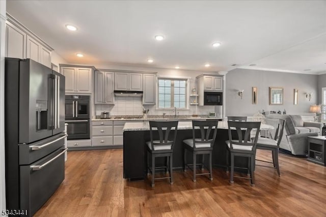 kitchen with gray cabinets, a sink, decorative backsplash, black appliances, and open floor plan