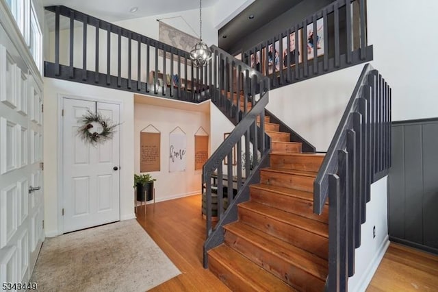 foyer entrance with a chandelier, a high ceiling, wood finished floors, and stairs