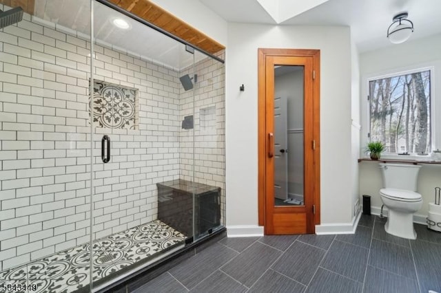 bathroom featuring baseboards, toilet, and a stall shower