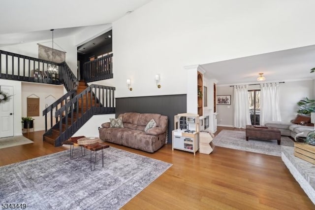 living area featuring baseboards, stairs, a high ceiling, wood finished floors, and a notable chandelier