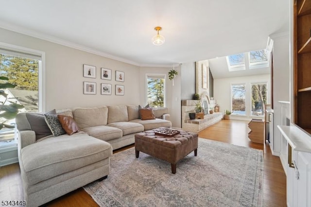 living room with a skylight, wood finished floors, a wealth of natural light, and ornamental molding