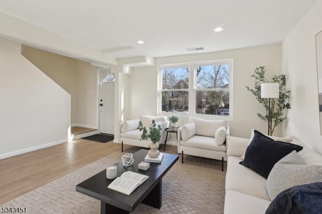 living room with recessed lighting, visible vents, baseboards, and wood finished floors