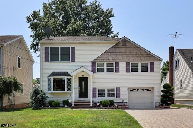 view of front of home with decorative driveway, an attached garage, and a front yard