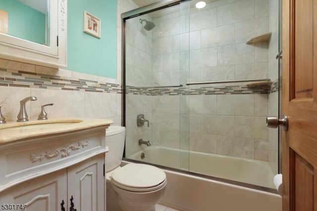 full bath featuring bath / shower combo with glass door, toilet, tile walls, and vanity