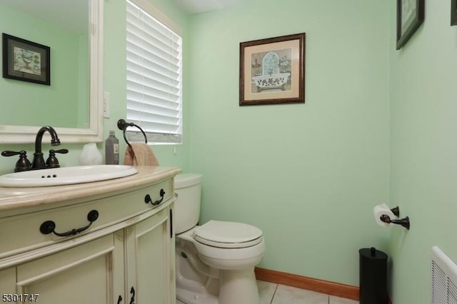 half bathroom with tile patterned floors, toilet, vanity, and baseboards