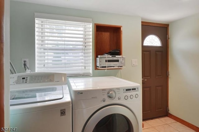 clothes washing area featuring washer and dryer, laundry area, light tile patterned floors, and baseboards