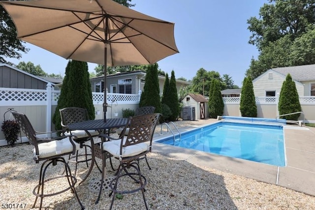 view of pool with an outbuilding, a patio, a fenced backyard, a storage shed, and a fenced in pool