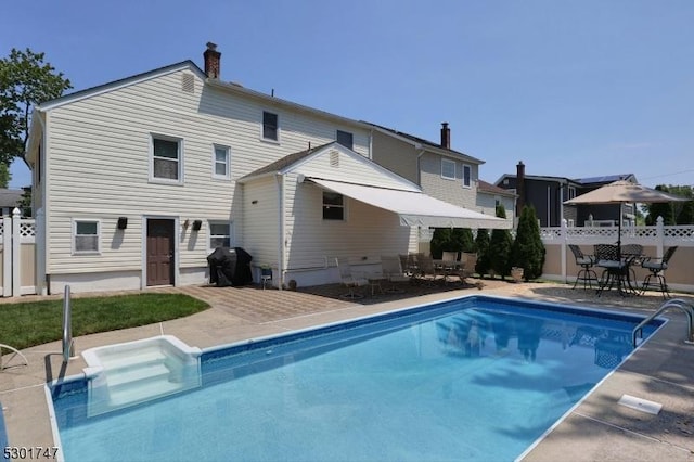 back of property with outdoor dining space, a patio, fence, a fenced in pool, and a chimney