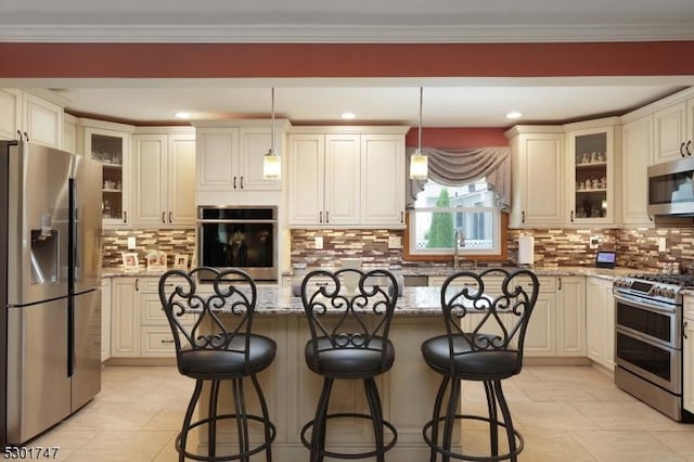 kitchen with a kitchen bar, light stone counters, backsplash, a kitchen island, and stainless steel appliances