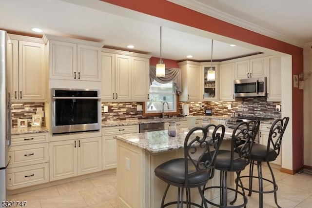 kitchen with a breakfast bar area, light stone counters, hanging light fixtures, appliances with stainless steel finishes, and crown molding