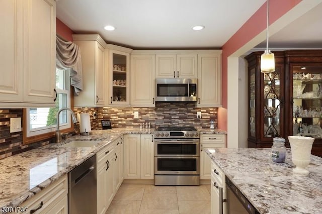 kitchen with a sink, cream cabinetry, light tile patterned floors, and stainless steel appliances