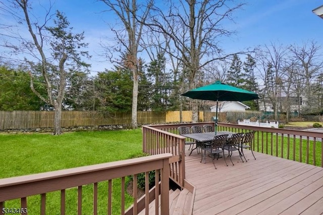 wooden terrace with outdoor dining area, a lawn, and fence