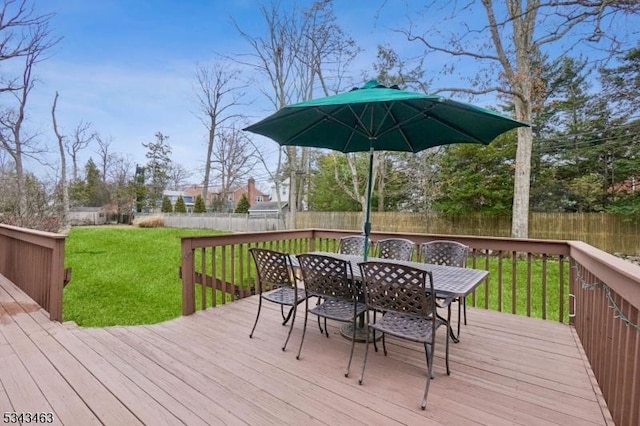 deck with outdoor dining area, a lawn, and fence