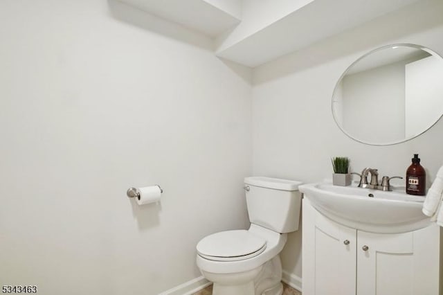 bathroom with toilet, vanity, and baseboards