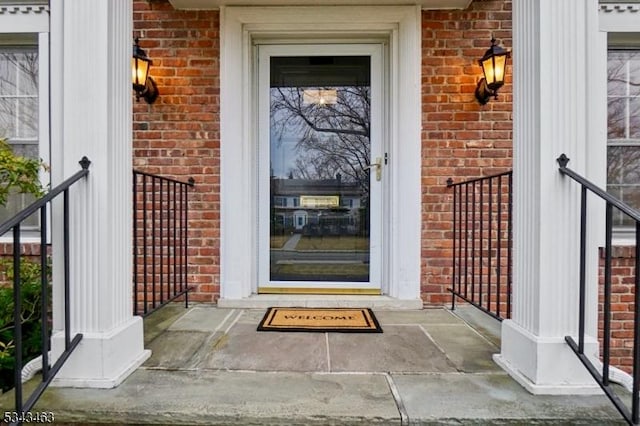 view of exterior entry with brick siding and a porch