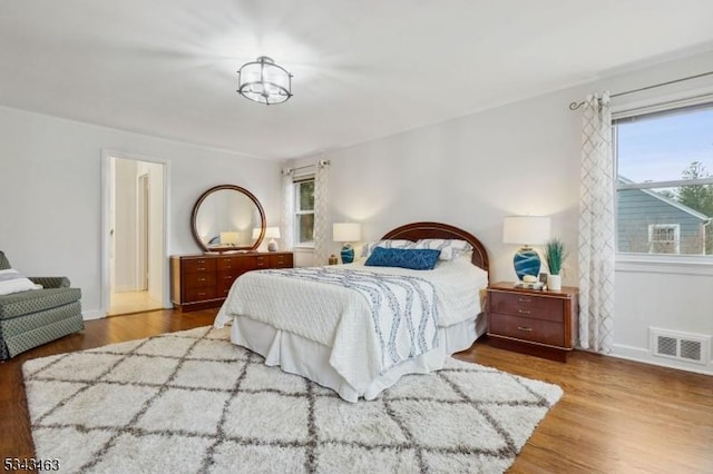 bedroom featuring visible vents, baseboards, and wood finished floors