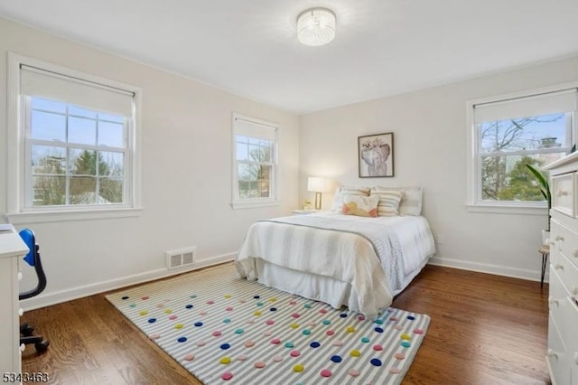 bedroom with visible vents, baseboards, and wood finished floors