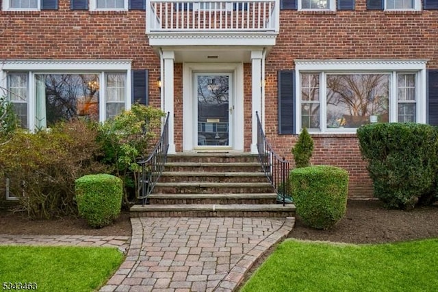 doorway to property with brick siding and a balcony