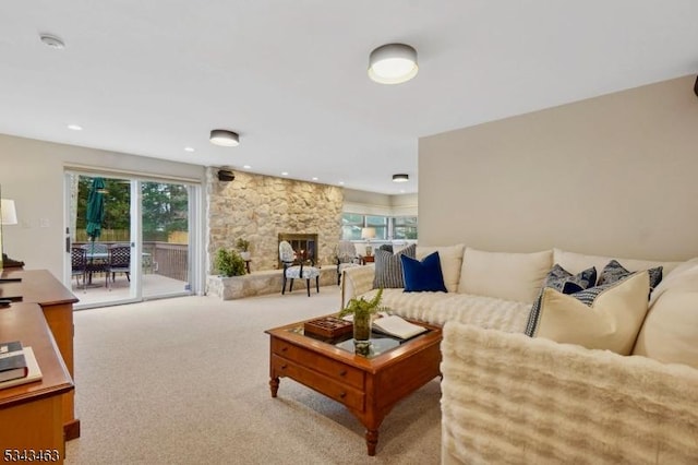 carpeted living area with a stone fireplace and recessed lighting