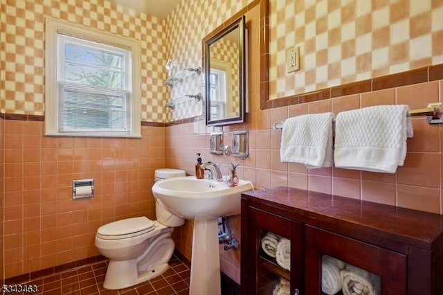 bathroom featuring tile patterned flooring, a wainscoted wall, toilet, and wallpapered walls