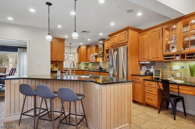 kitchen featuring visible vents, brown cabinets, stainless steel appliances, wall chimney exhaust hood, and a sink