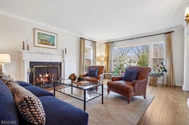 living room with baseboards, light wood-style floors, a high end fireplace, and crown molding